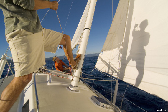 Low section view of a man pulling a rope on a sailboat
