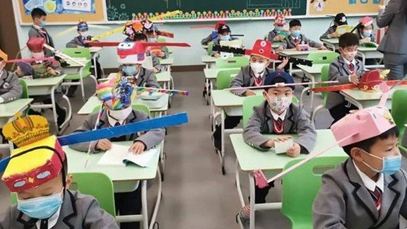 contioutra.com - Na China, crianças voltam às aulas com 'chapéu-helicóptero' para garantir distância dos colegas