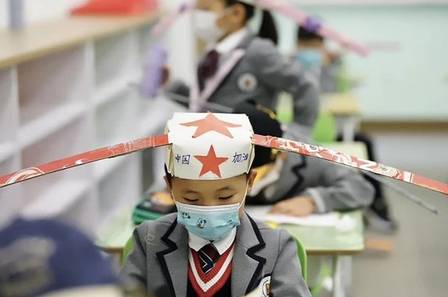 contioutra.com - Na China, crianças voltam às aulas com 'chapéu-helicóptero' para garantir distância dos colegas