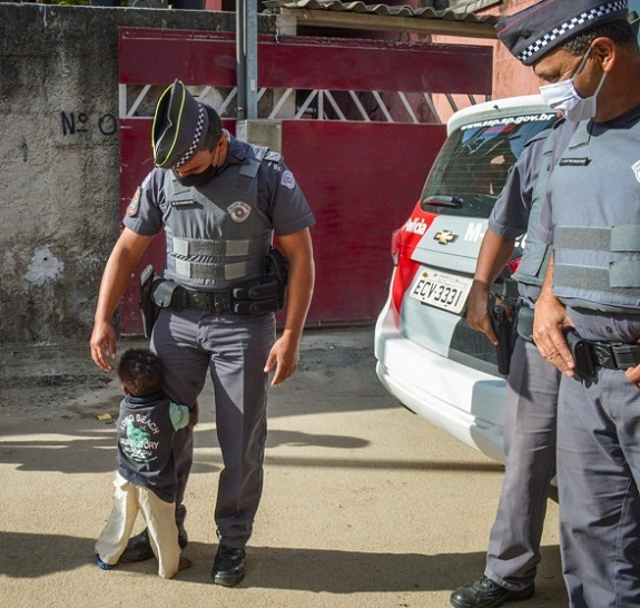 contioutra.com - Menininho abraça policial depois de receber cesta básica em Itaquaquecetuba-SP