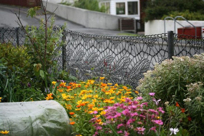 contioutra.com - Essa mulher trocou as grades de seu jardim por cercas que ela mesmo tricotou. O resultado é lindo!