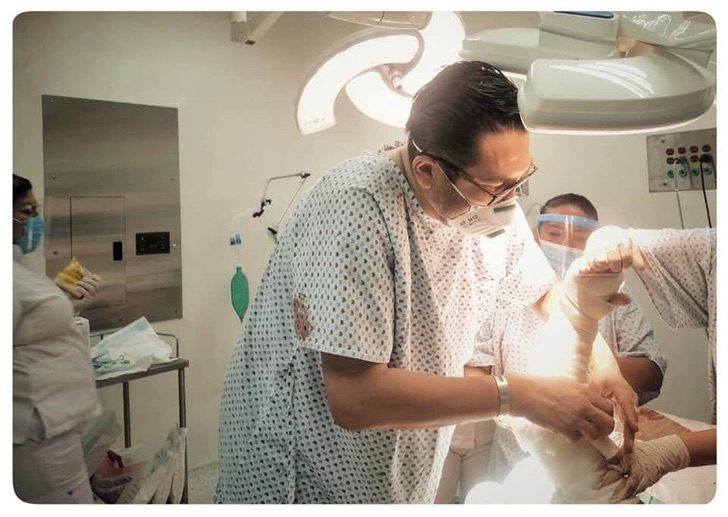 contioutra.com - Médico sendo atendido em sala de emergência se levanta da cama para ajudar outro paciente.