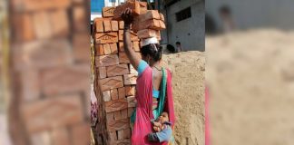 Mãe trabalha carregando tijolos na cabeça com o filho no colo