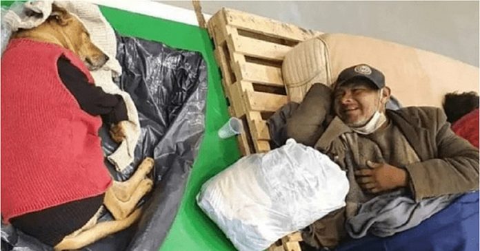 Homem em situação de rua sorri para seu cachorro após abrigo os acolherem em noite fria